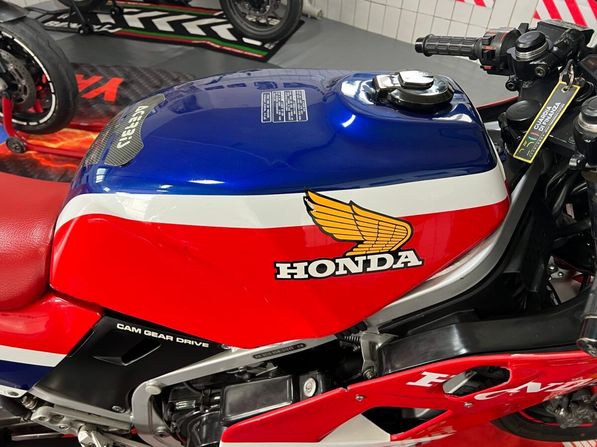 Serbatoio di una motocicletta Honda rosso, bianco e blu con logo Honda alato giallo.