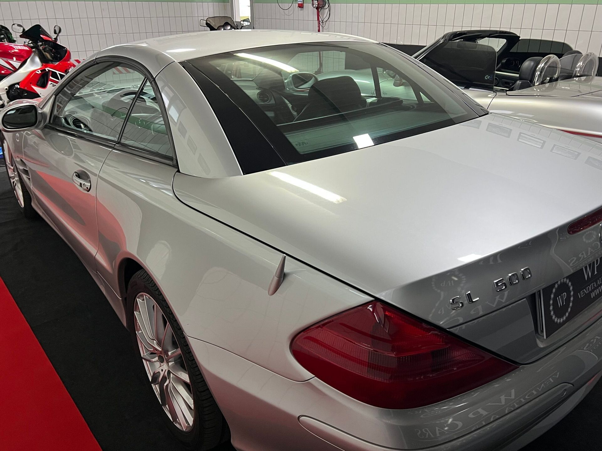 Mercedes-Benz SL 320 decappottabile color argento in uno showroom. Fanale posteriore rosso, interni neri.