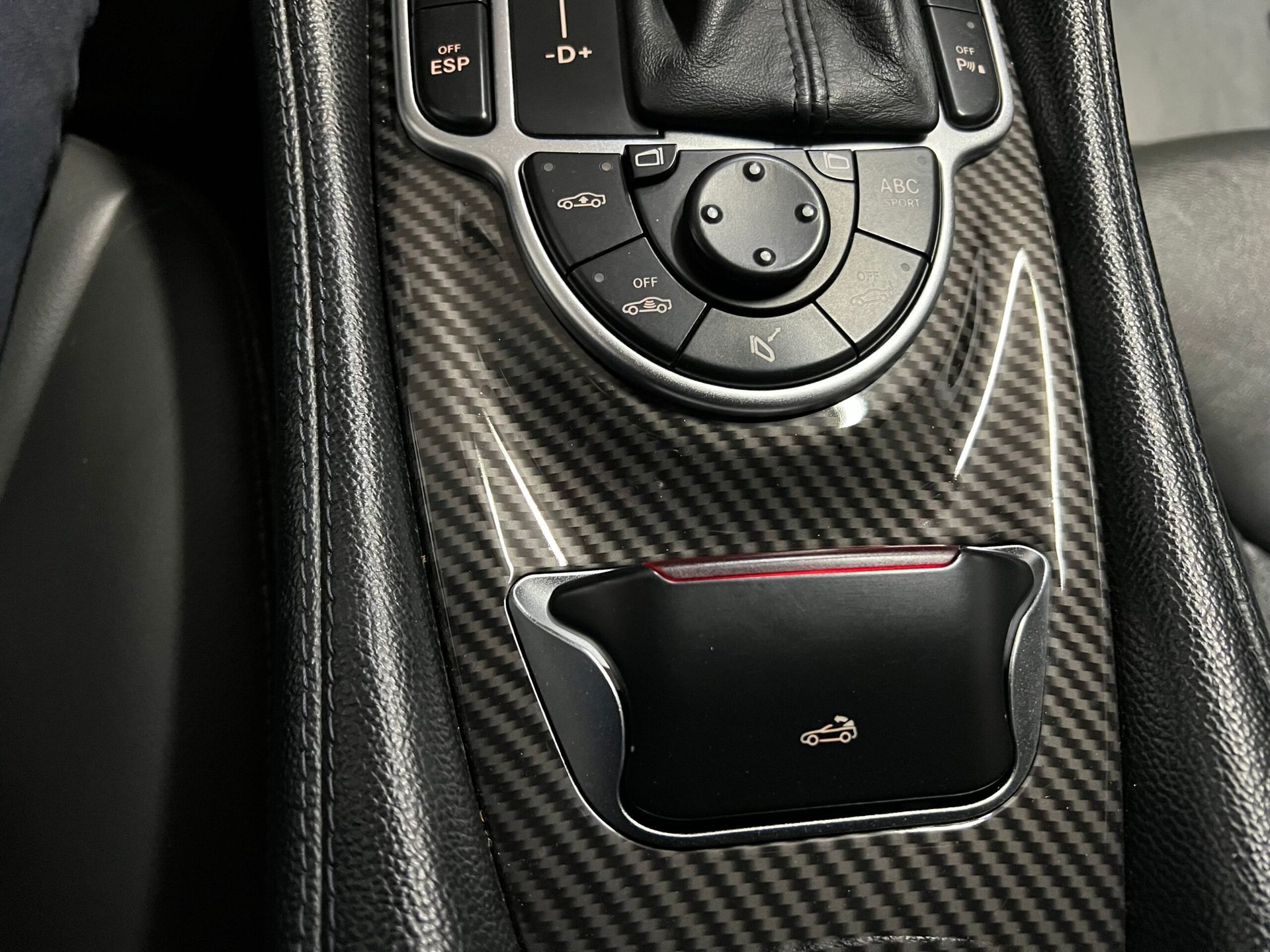 Console per auto in fibra di carbonio con comandi e un piccolo vano portaoggetti.