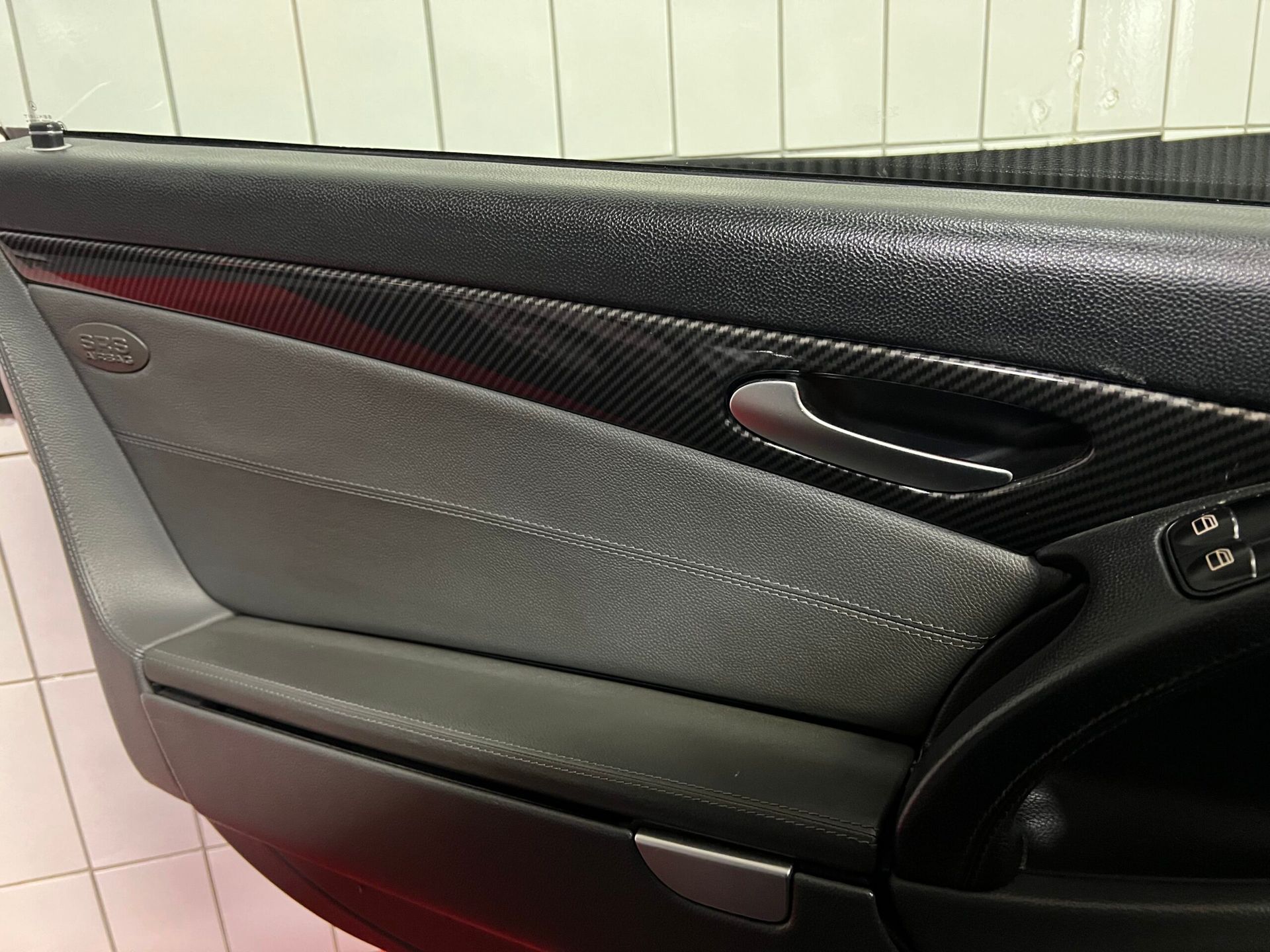 Interni delle portiere con dettagli grigi e neri, tra cui finiture in fibra di carbonio e maniglia della portiera.