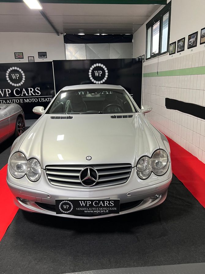 Mercedes-Benz SL argentata in un garage con pavimento nero e rosso, circondata dal marchio VP Cars.
