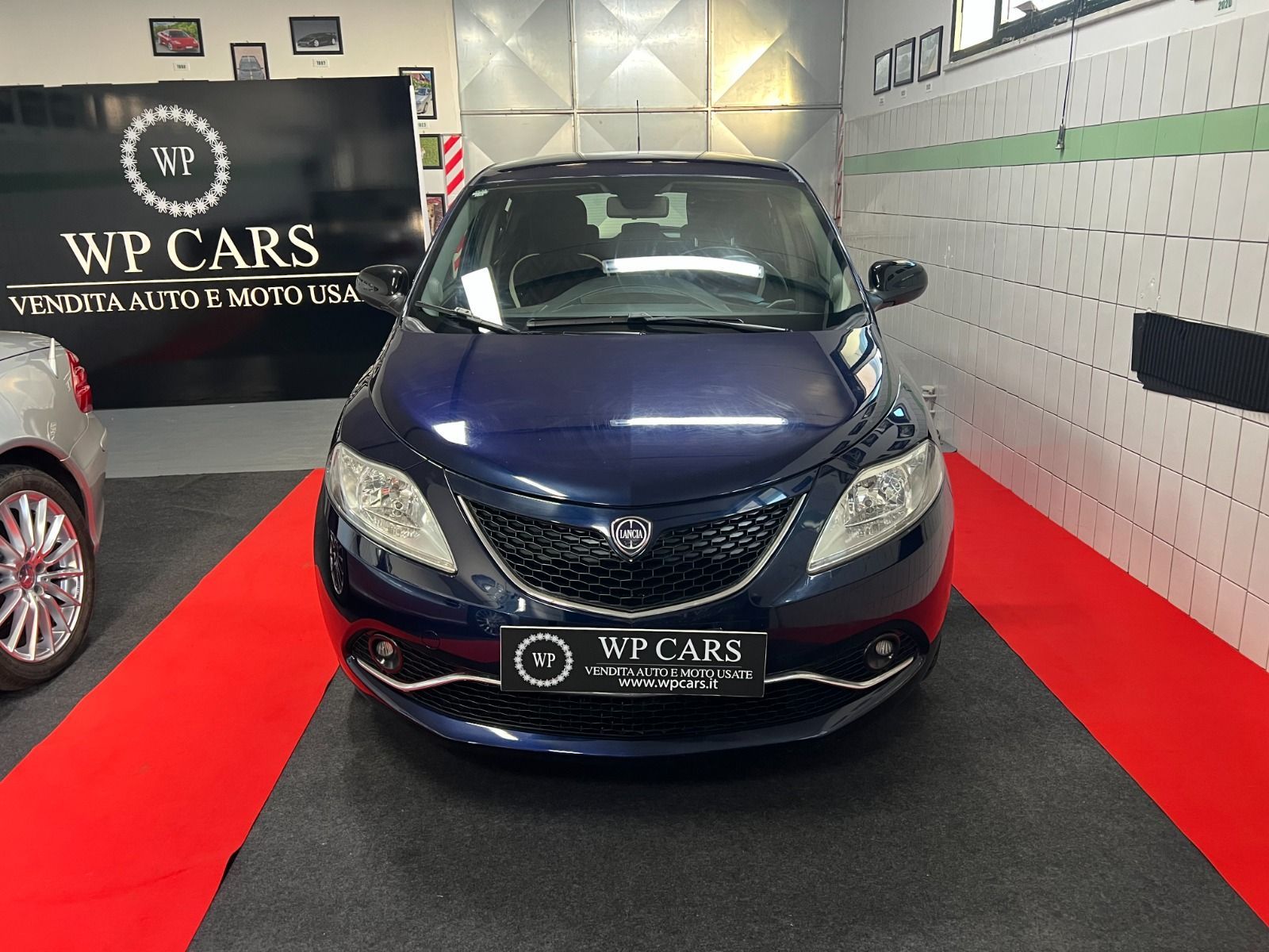 SUV Opel Mokka bianco parcheggiato in uno showroom con interni neri e rossi.