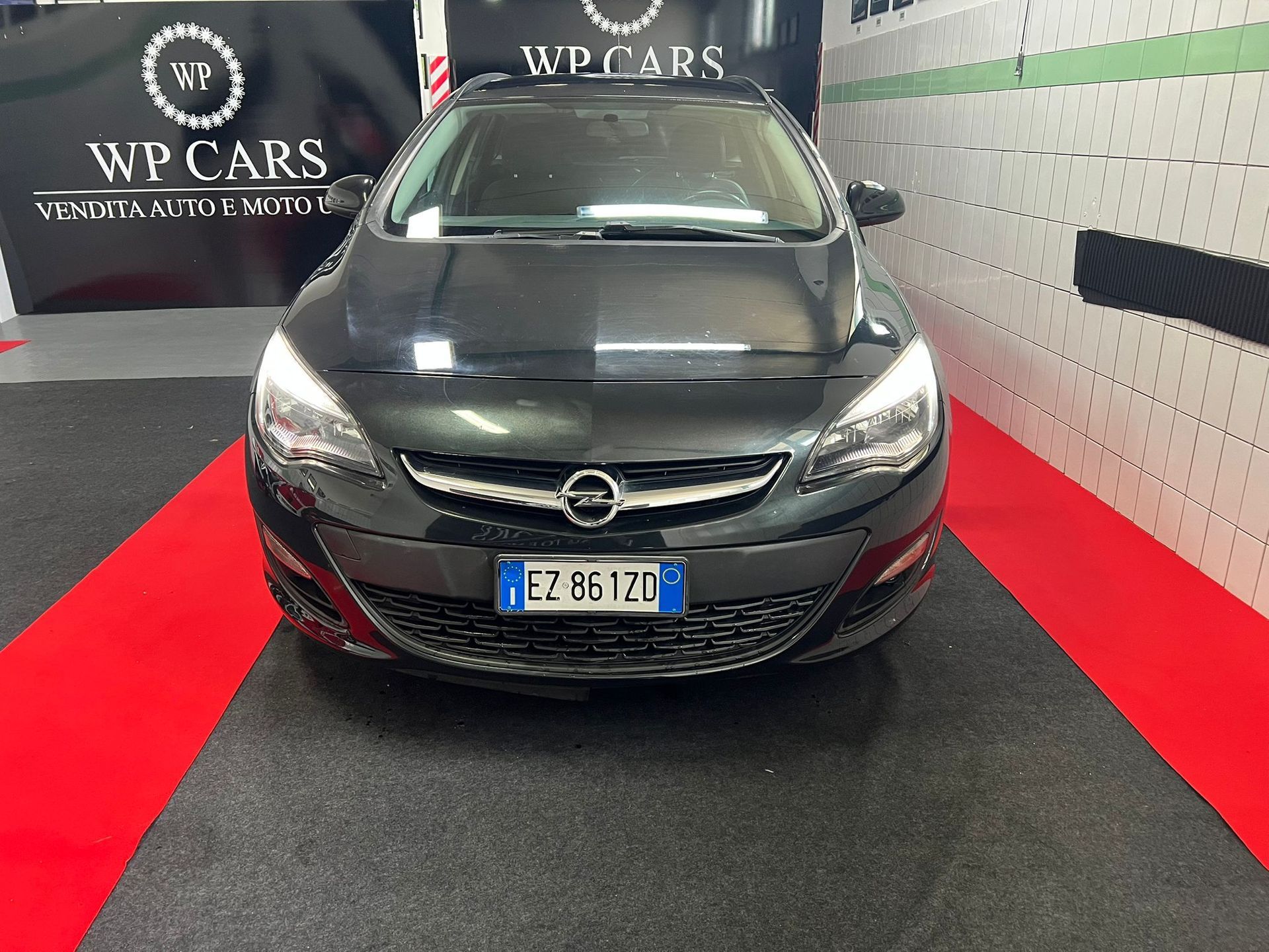 SUV Opel Mokka bianco parcheggiato in uno showroom con interni neri e rossi.