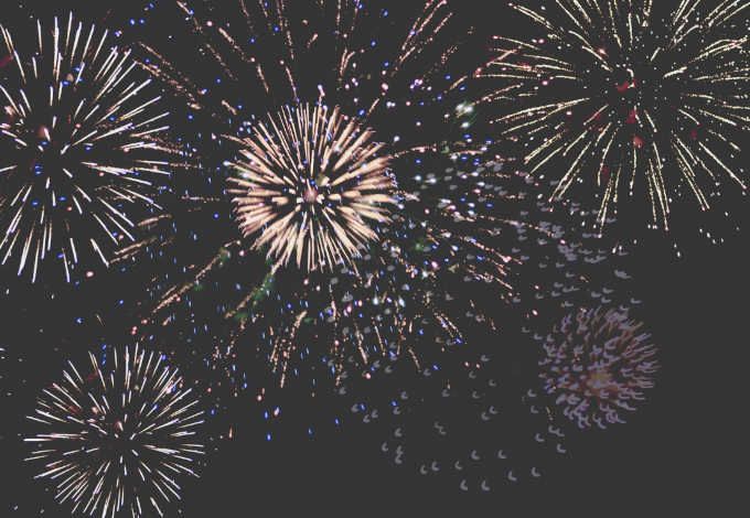 Fireworks explode in various colors against a dark night sky.