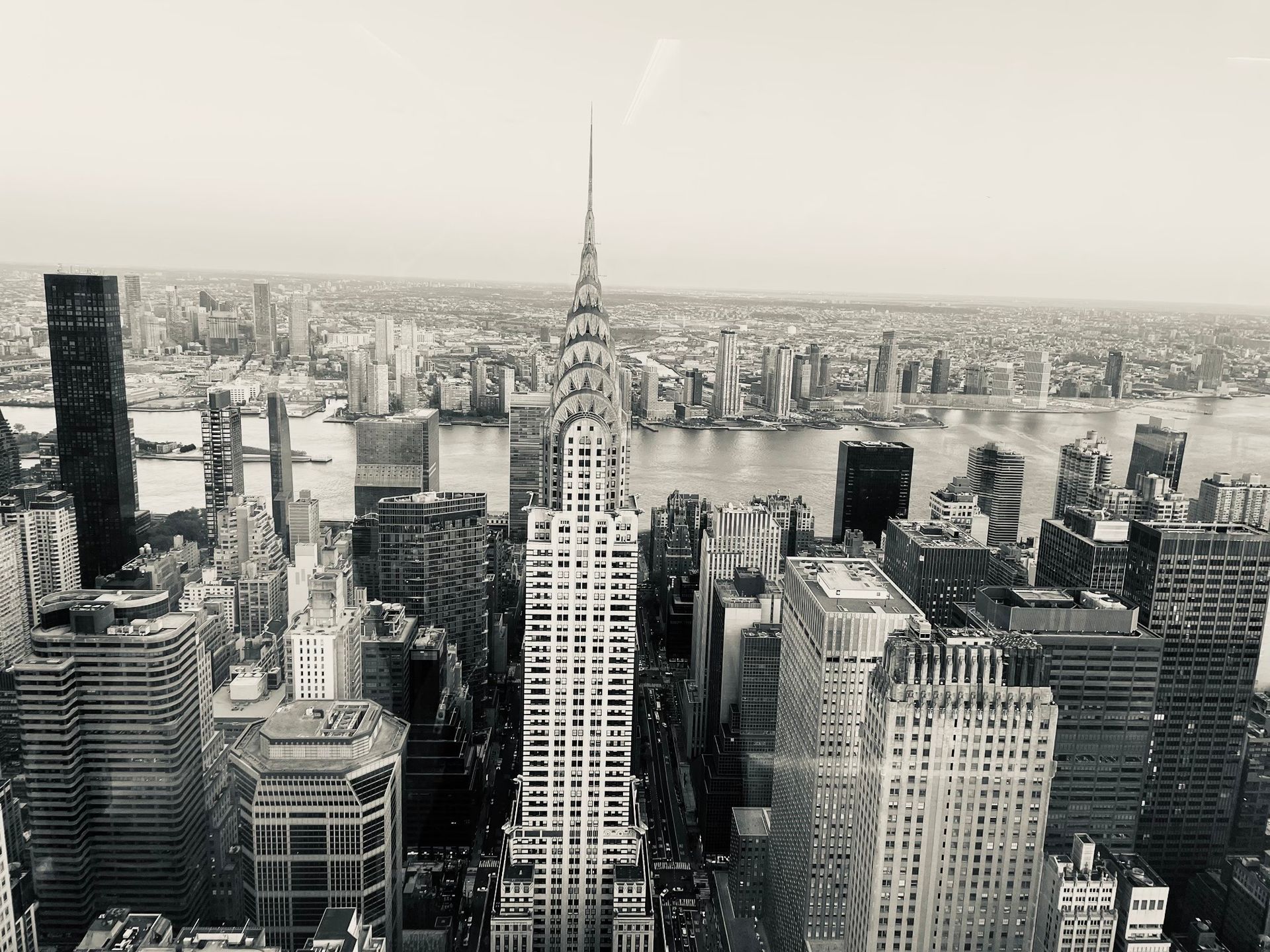 Black and white high-angle view of the Art Deco Chrysler Building surrounded by the dense skyscrapers of New York City.