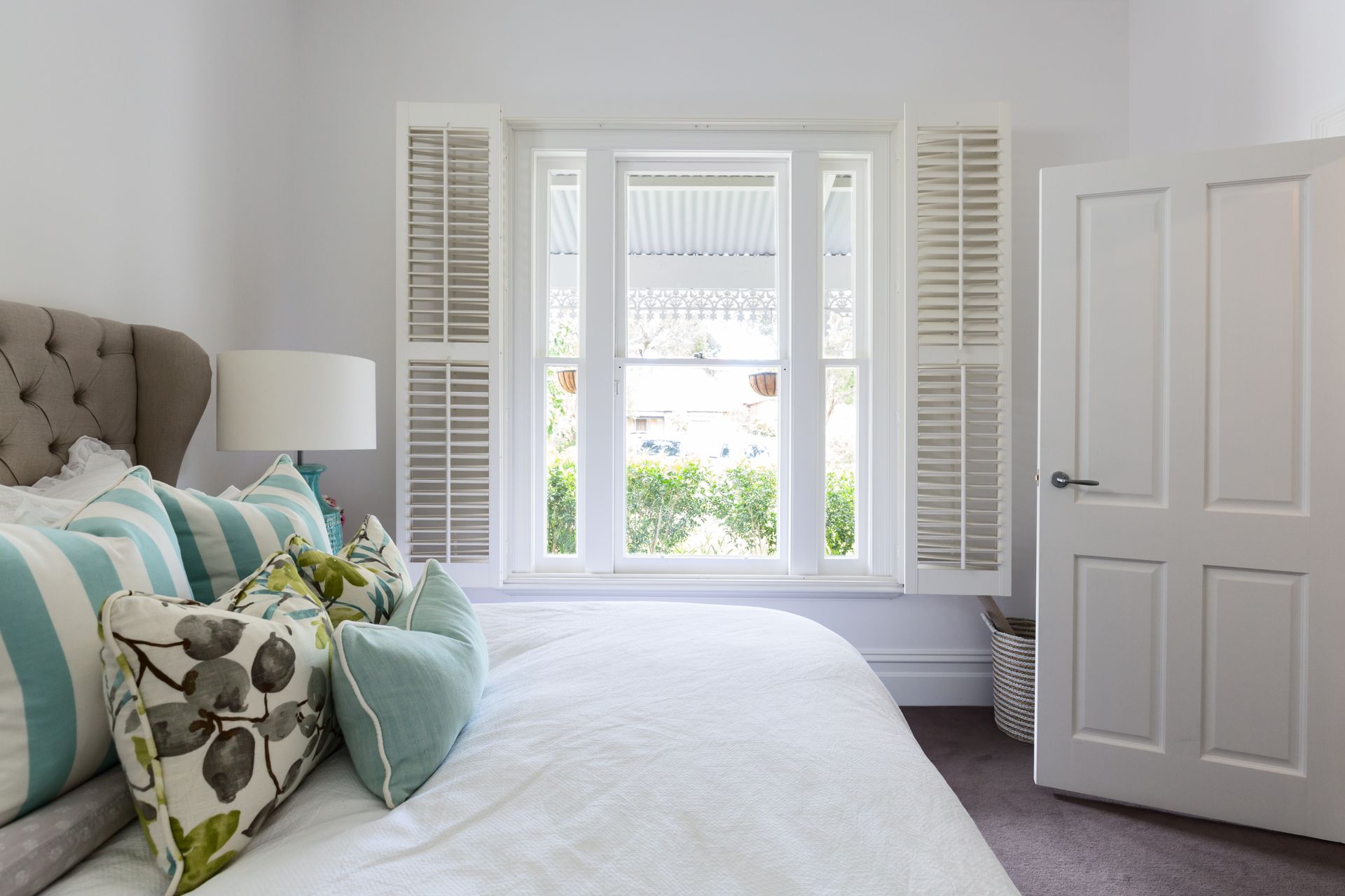 a bedroom with a bed and a window with shutters All Window Decor (817) 448-3393. services