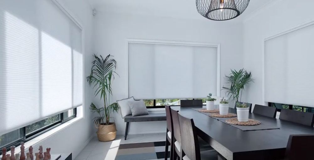 a dining room with a long table and chairs and white honeycomb shades All Window Decor (817) 448-3393.