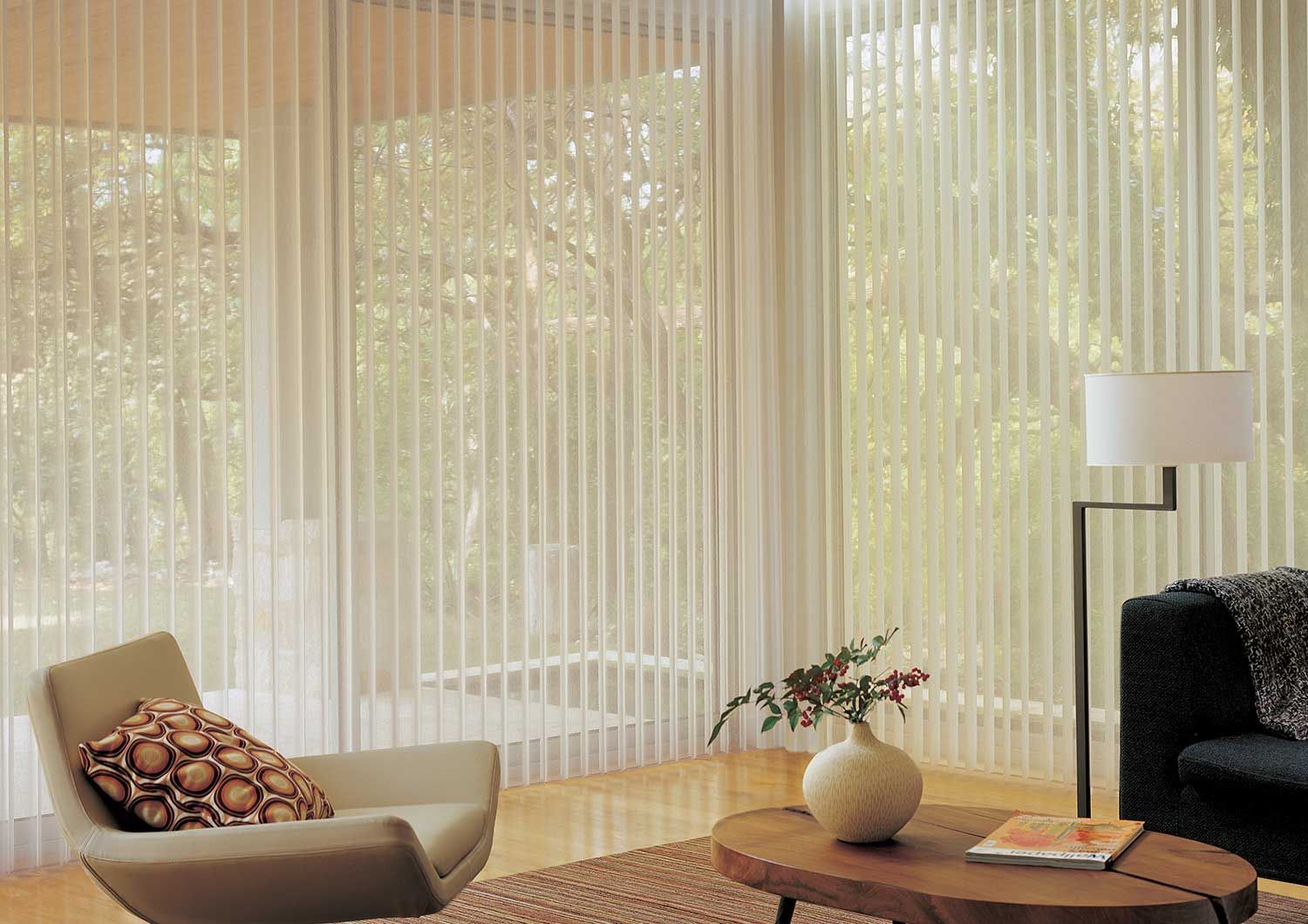 a living room with a chair a table and a lamp and vertical blinds All Window Decor (817) 448-3393