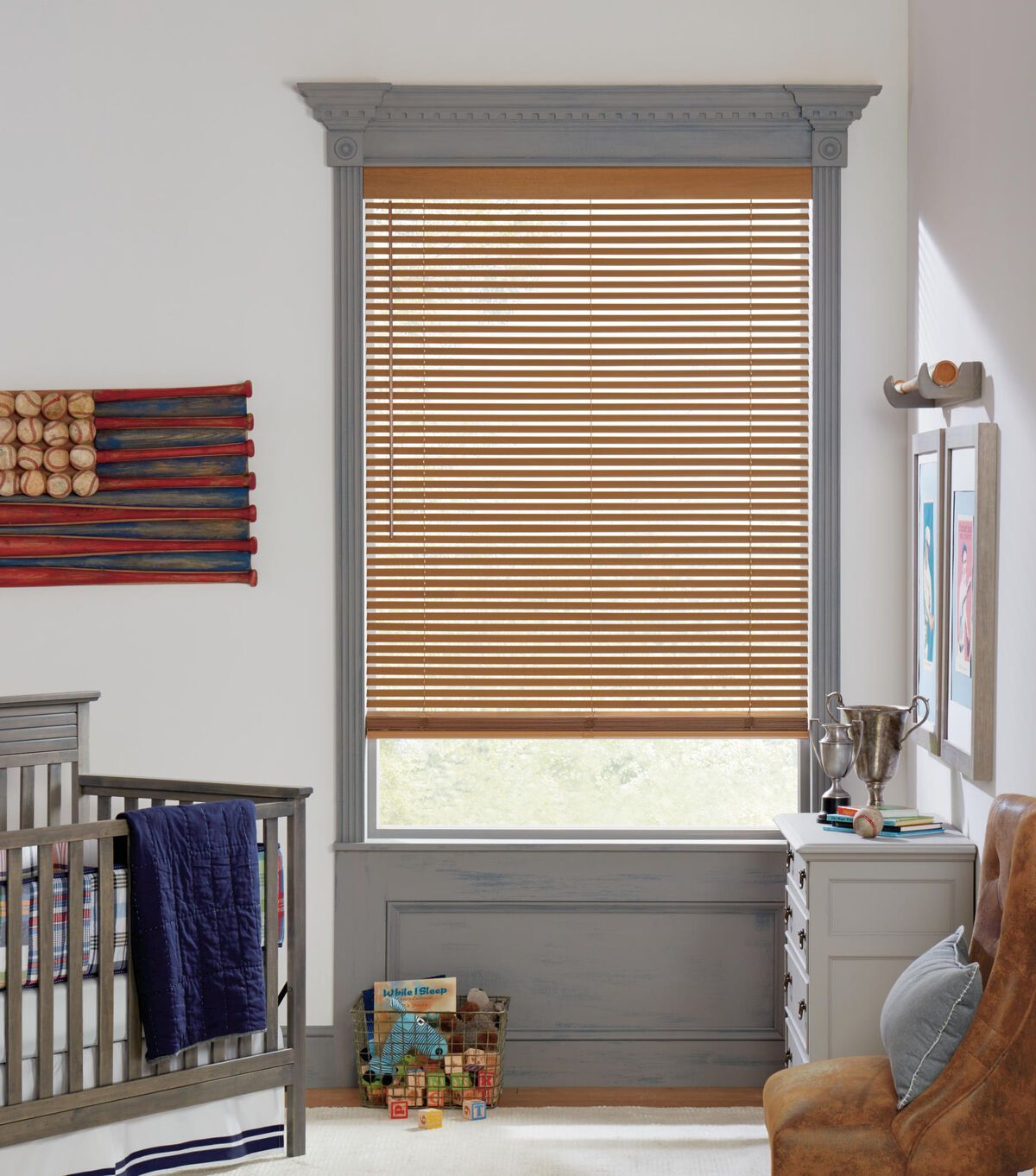 a child 's room with a crib , chair , dresser and window with blinds All Window Decor (817) 448-3393.