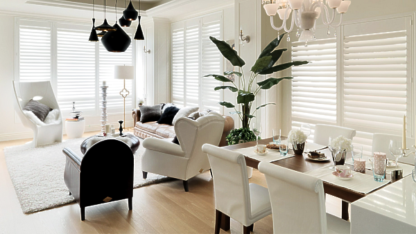 a living room with a dining table and chairs and a couch and shuttered windows All Window Decor (817) 448-3393.