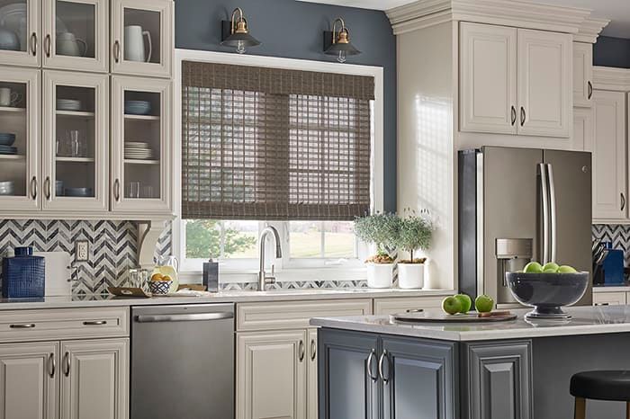 a kitchen with white cabinets , stainless steel appliances , and a large island with woven wood shades All Window Decor (817) 448-3393.