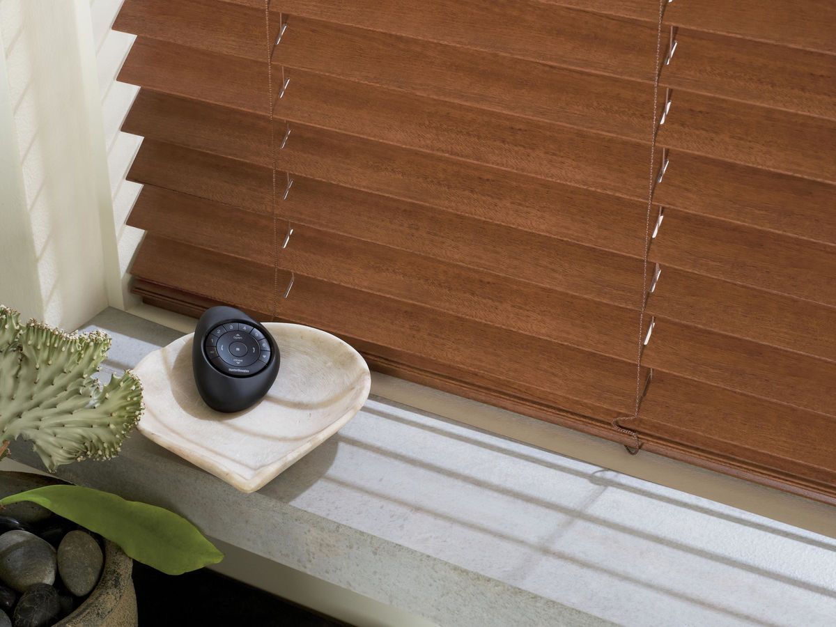 A wooden blind with a remote control on the window sill