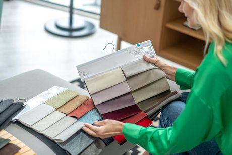 a woman in a green shirt is looking at fabric samples All Window Decor (817) 448-3393.