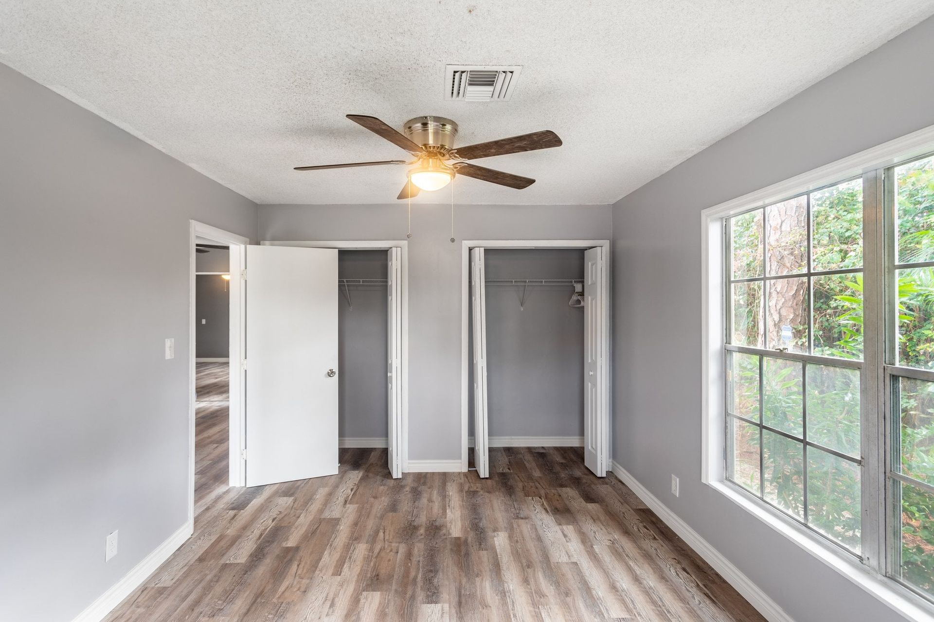 an empty bedroom with a ceiling fan and a lot of windows .