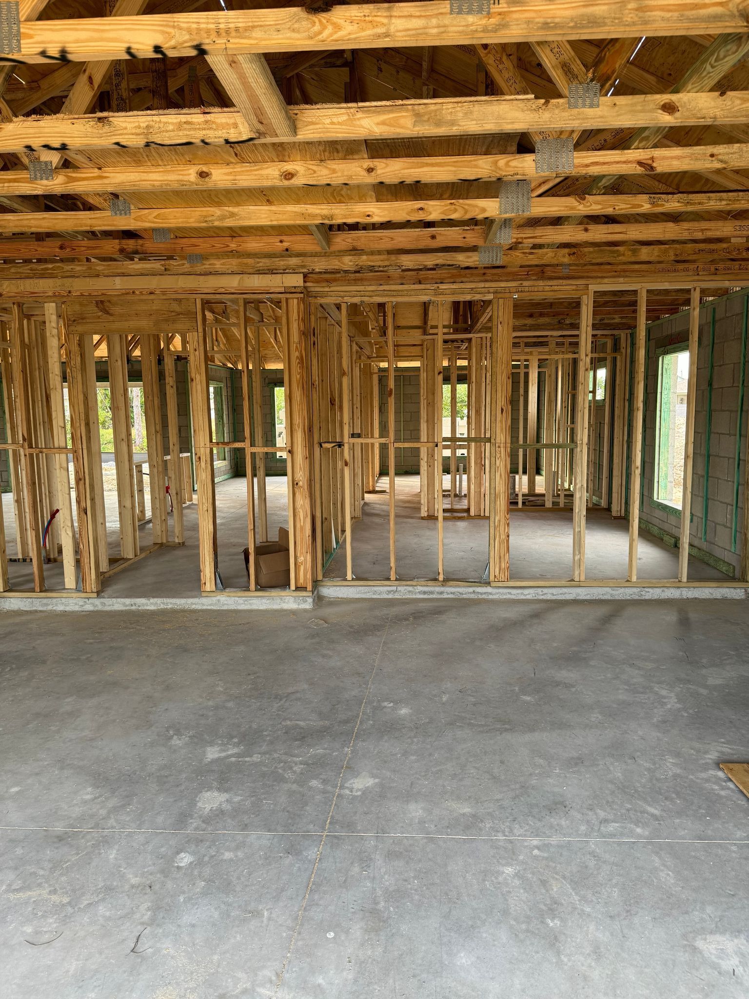 the inside of a building under construction with wooden beams and a concrete floor .