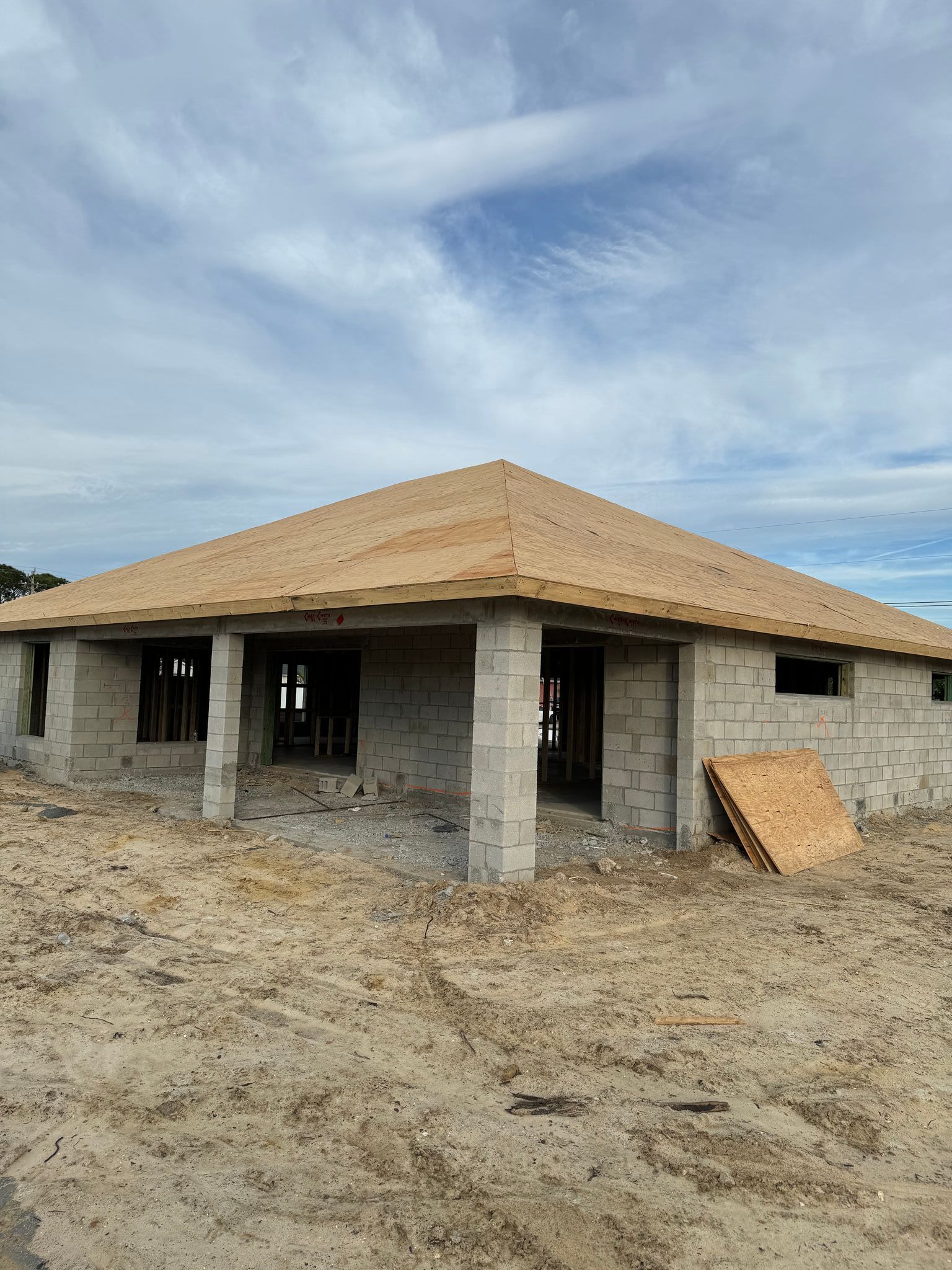 a house is being built in a dirt field with a wooden roof .