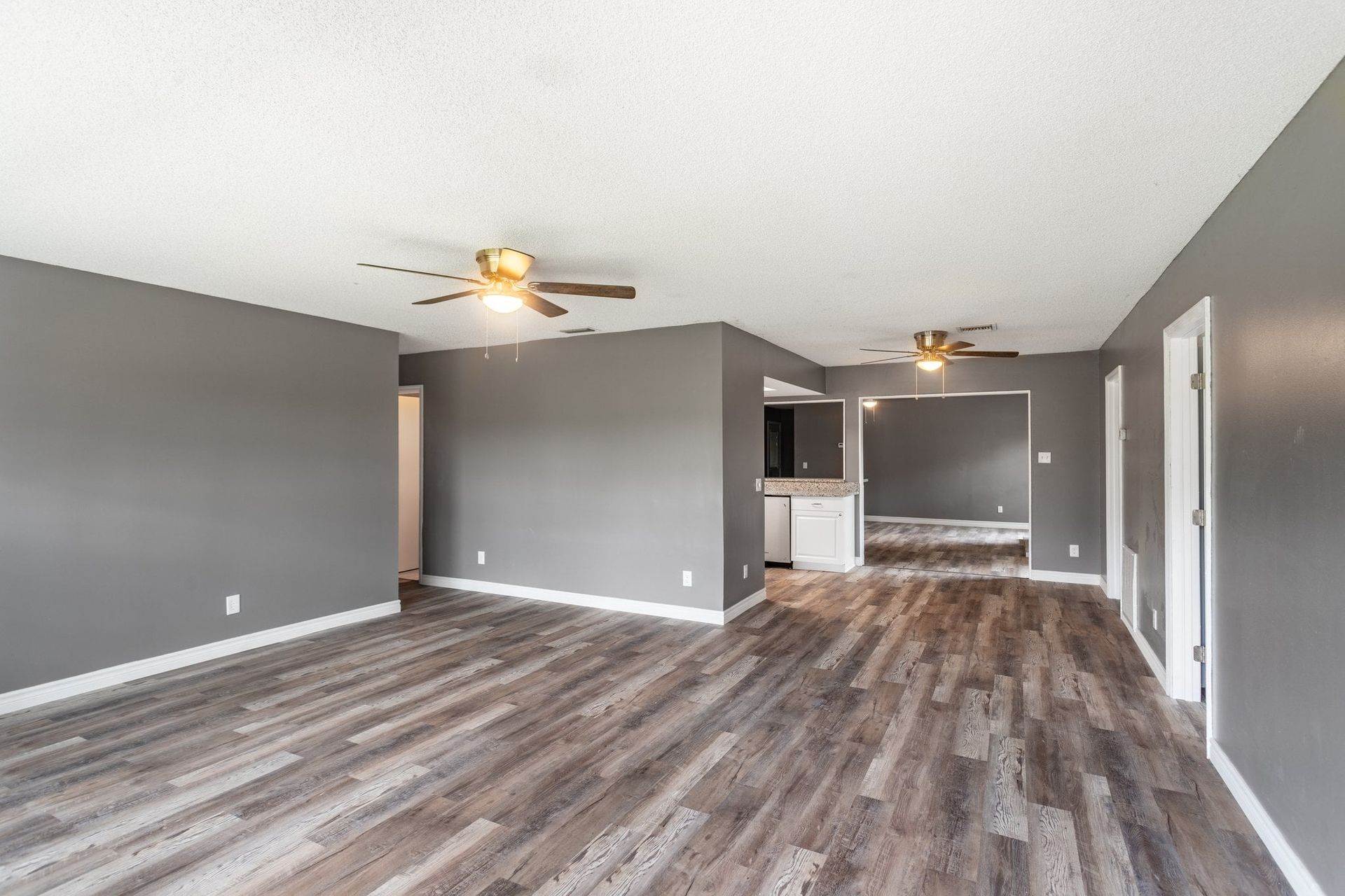 an empty living room with hardwood floors and a ceiling fan .