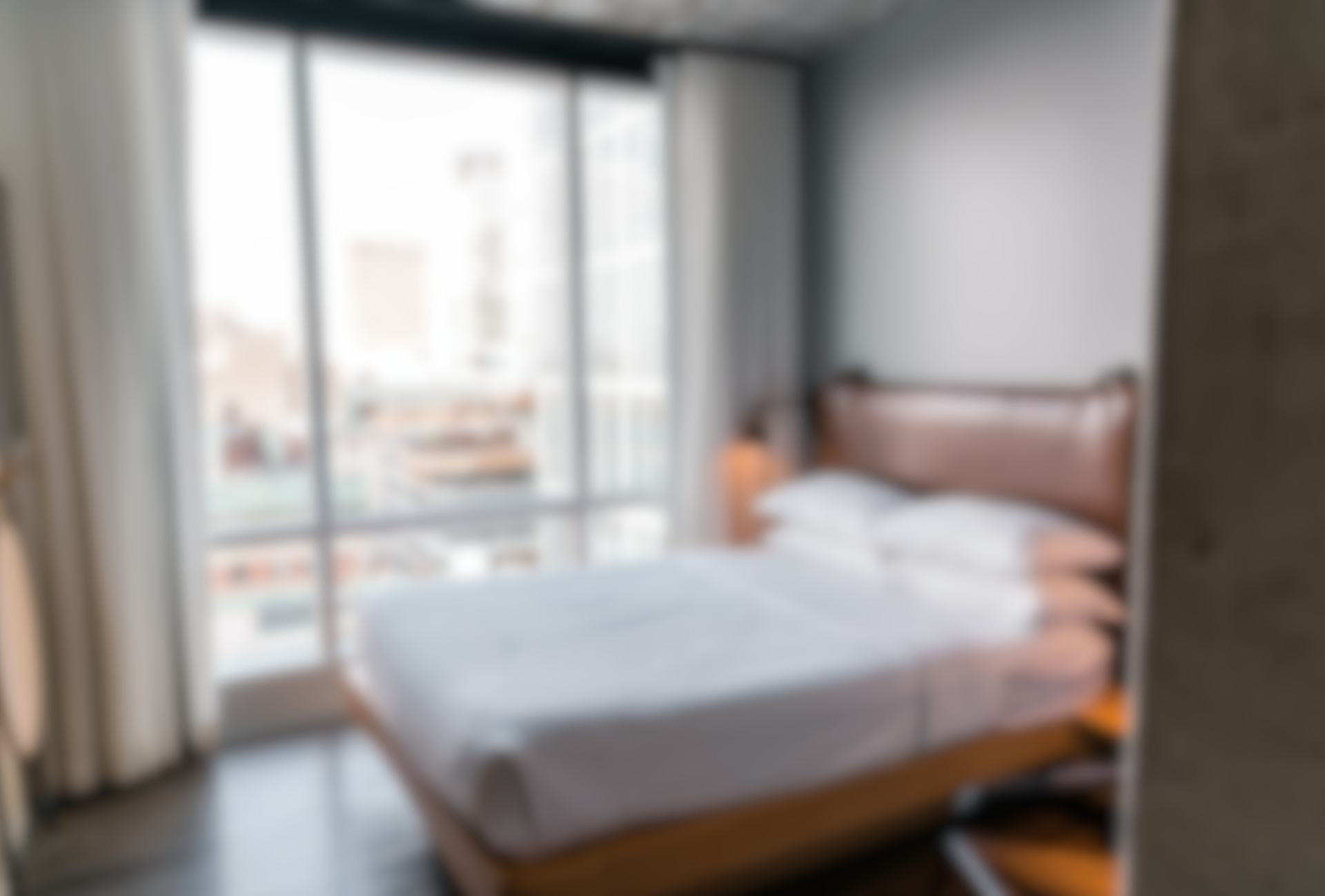 a blurry picture of a hotel room with a bed and a large window .