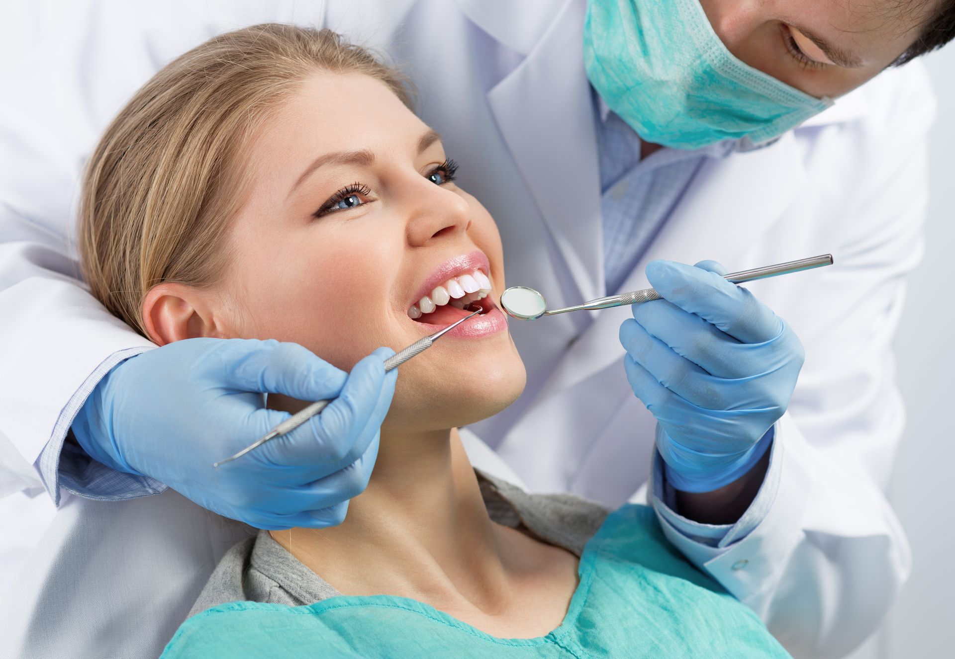 a woman is getting her teeth examined by a dentist