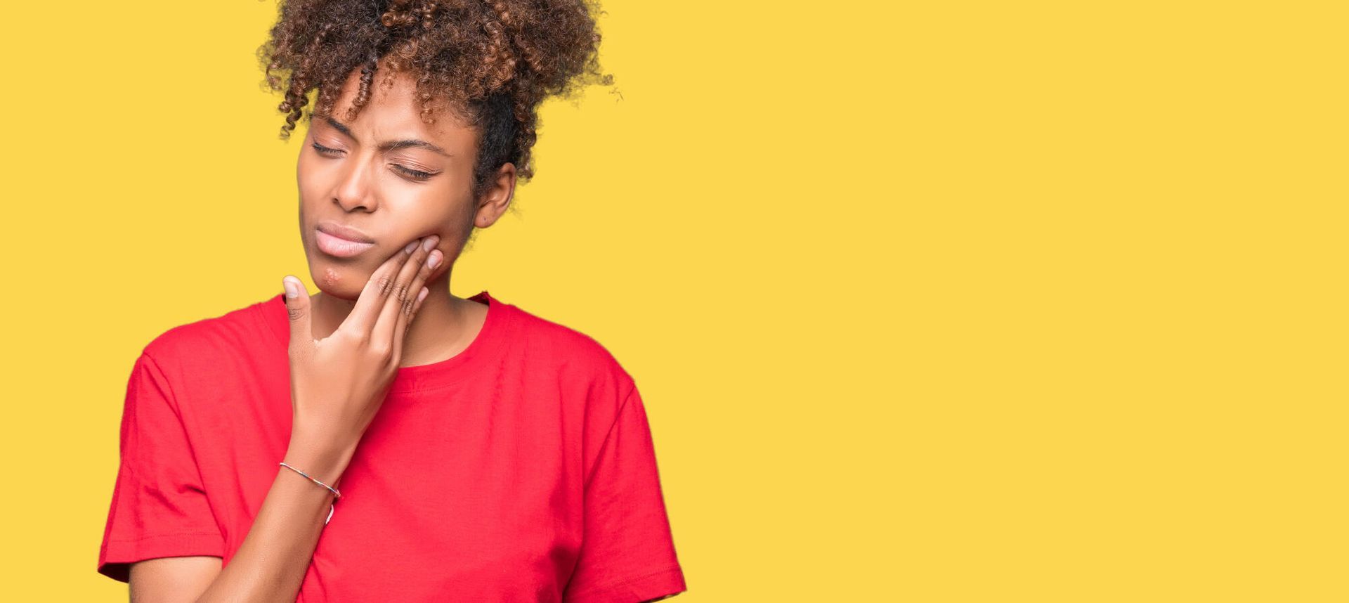 A young woman is holding her face in pain because of a toothache.