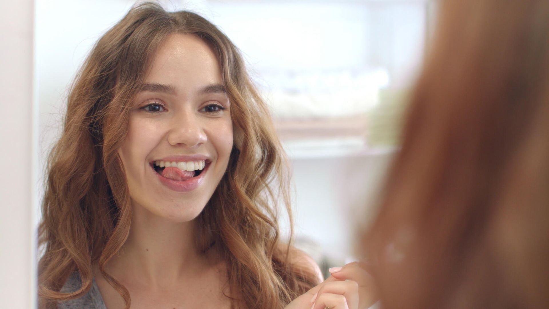 Dentist examining patient's teeth. Patient smiles in chair, dentist wears mask and gown.