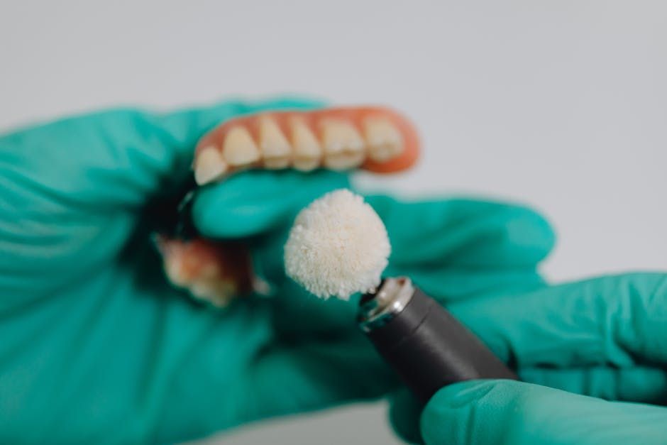 A dentist is polishing a denture with a machine.