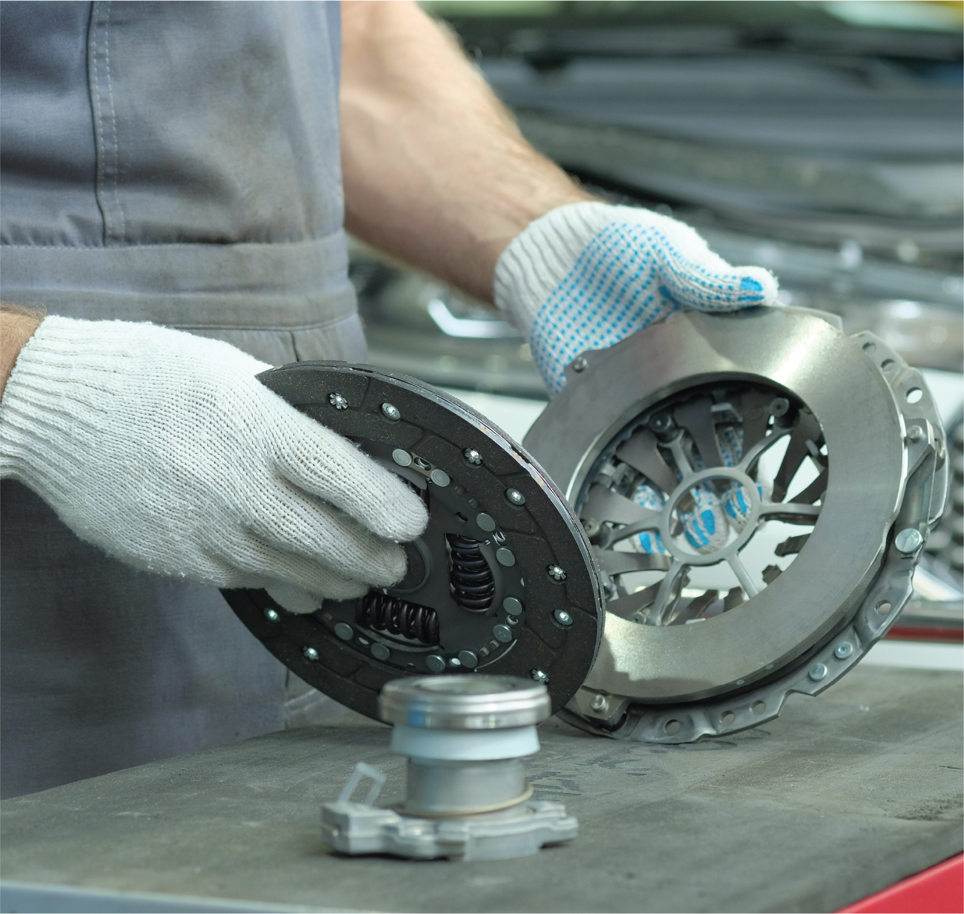 A man wearing gloves is working on a clutch disc