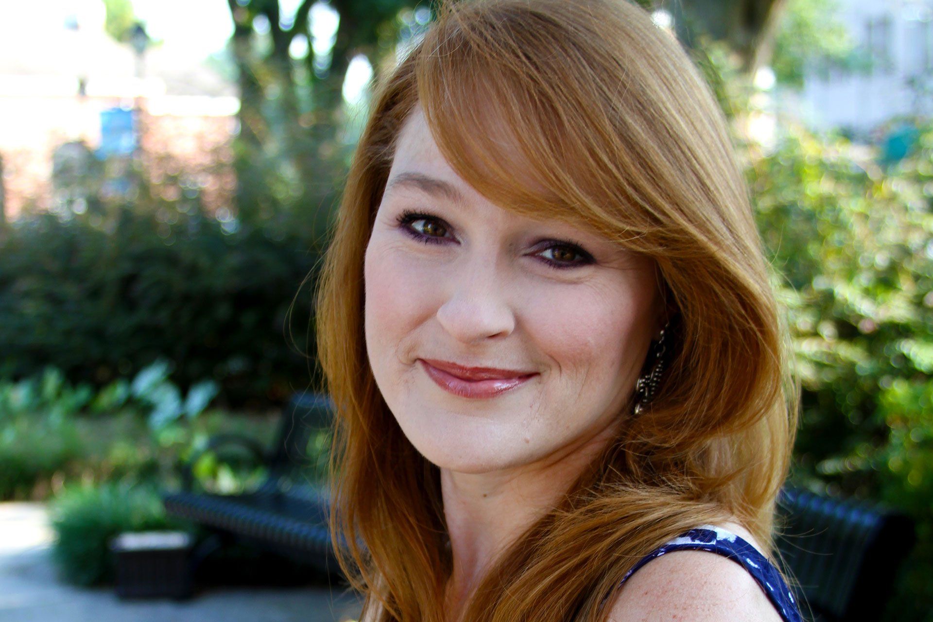 A woman with red hair and freckles is smiling for the camera.