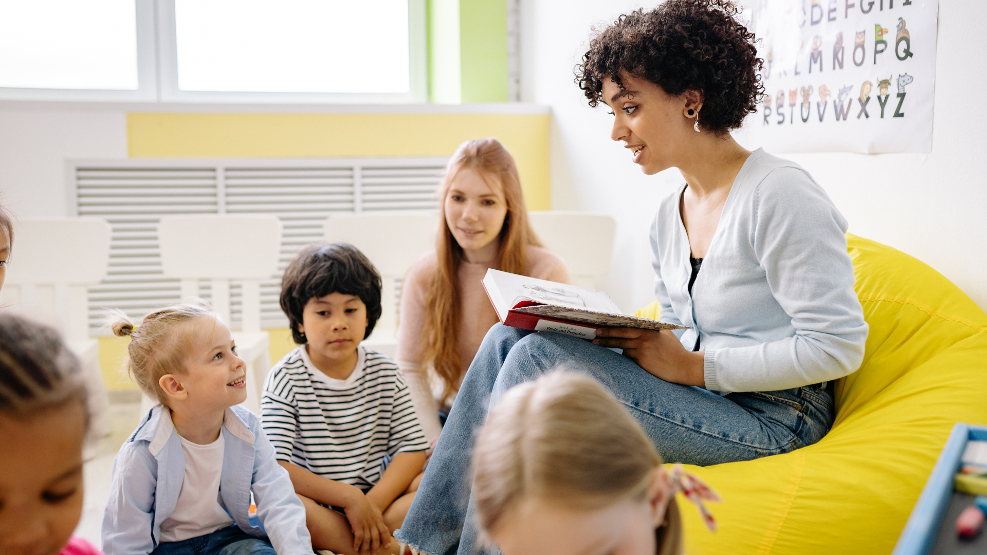 A family is sitting on a couch reading a book together.
