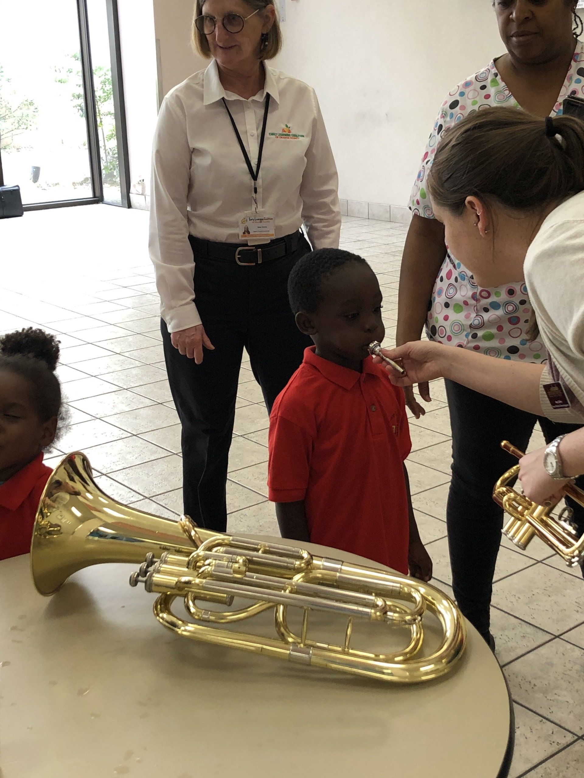 A group of people are standing around a table looking at a trumpet.