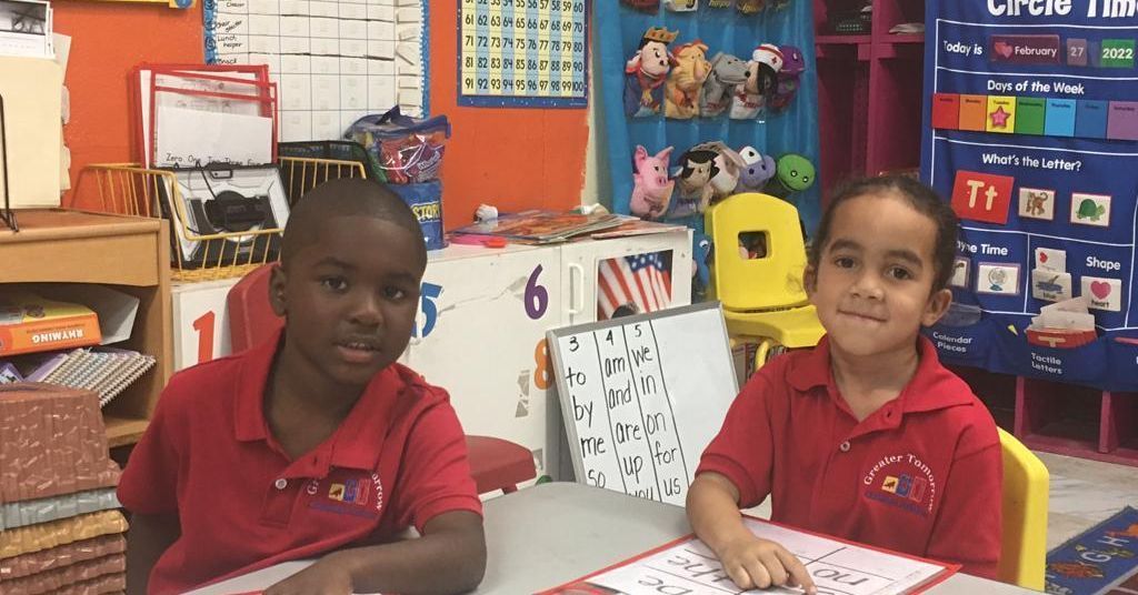 A boy and a girl are sitting at a table in a classroom.