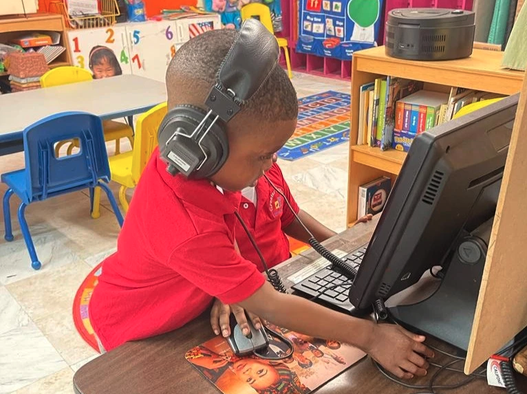 A young boy wearing headphones is using a computer