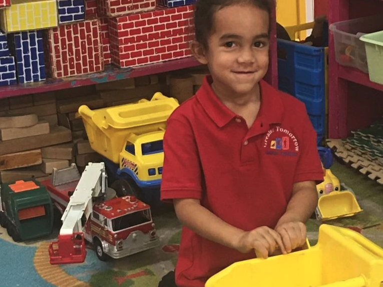 A young boy in a red shirt is playing with toys in a room.