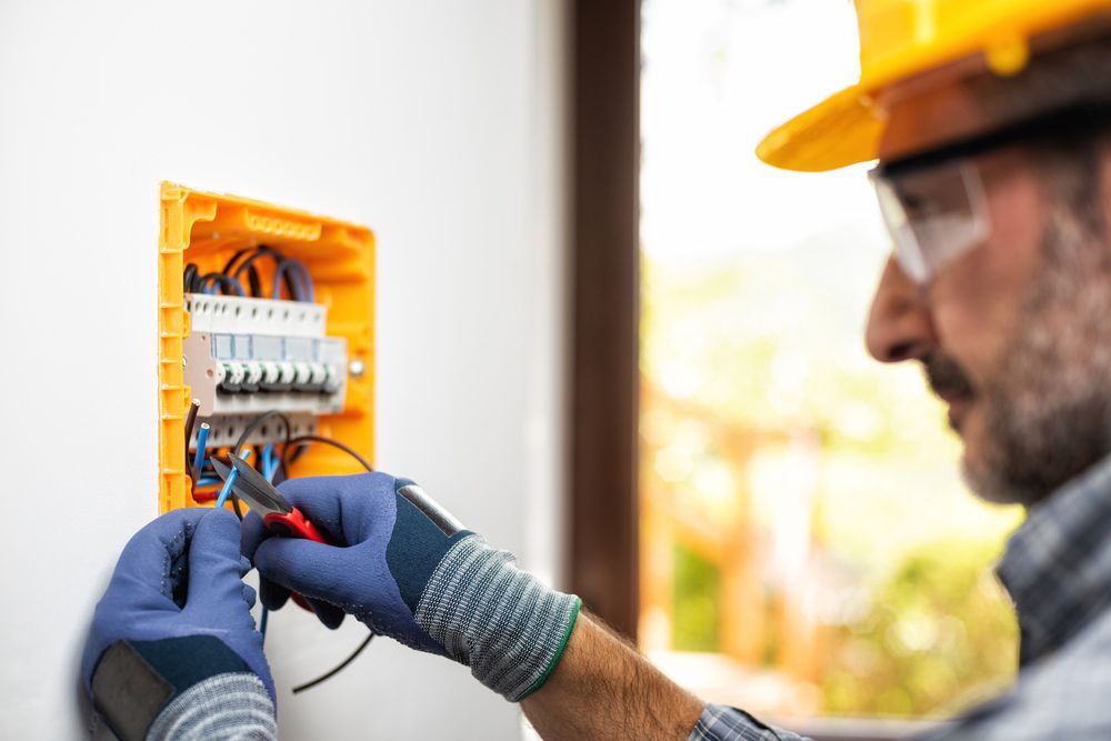 An Electrician Is Working On An Electrical Box On A Wall — IPOWER Industries In Cannonvale, QLD