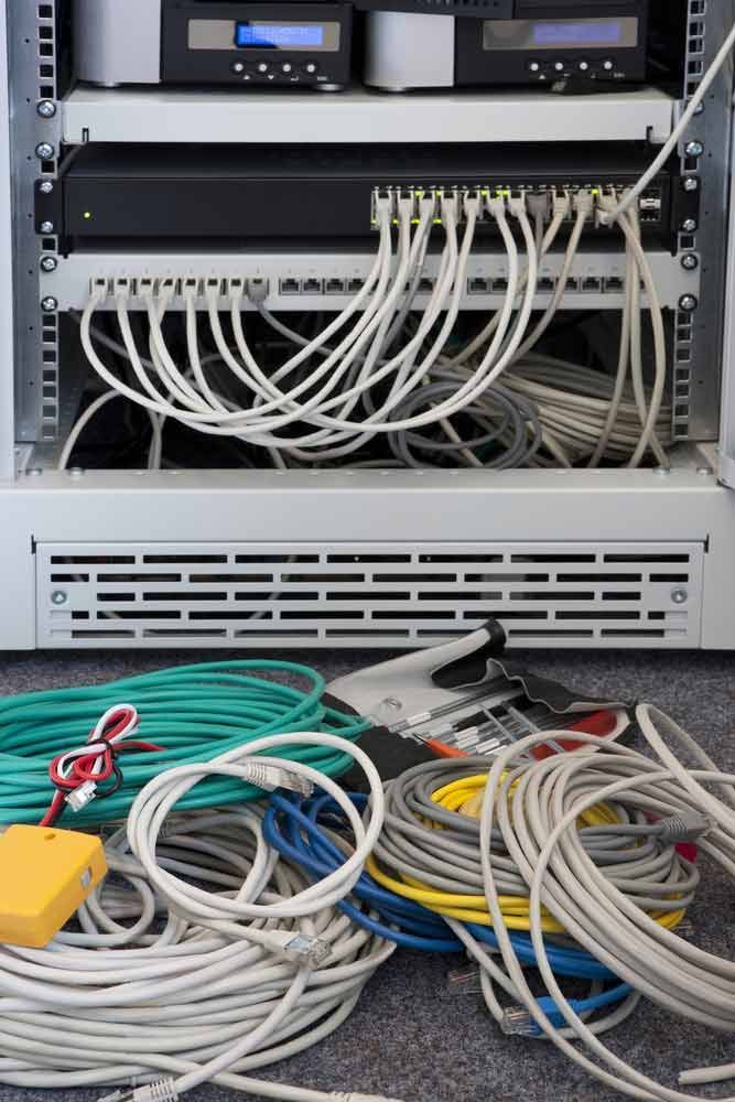 A Bunch Of Wires Are Laying On The Floor In Front Of A Server Rack — IPOWER Industries In Airlie Beach, QLD