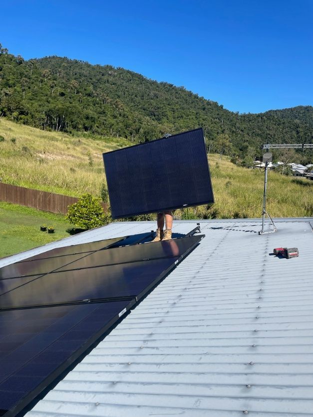 A Person Is Holding A Solar Panel On Top Of A Roof — IPOWER Industries In Strathdickie, QLD