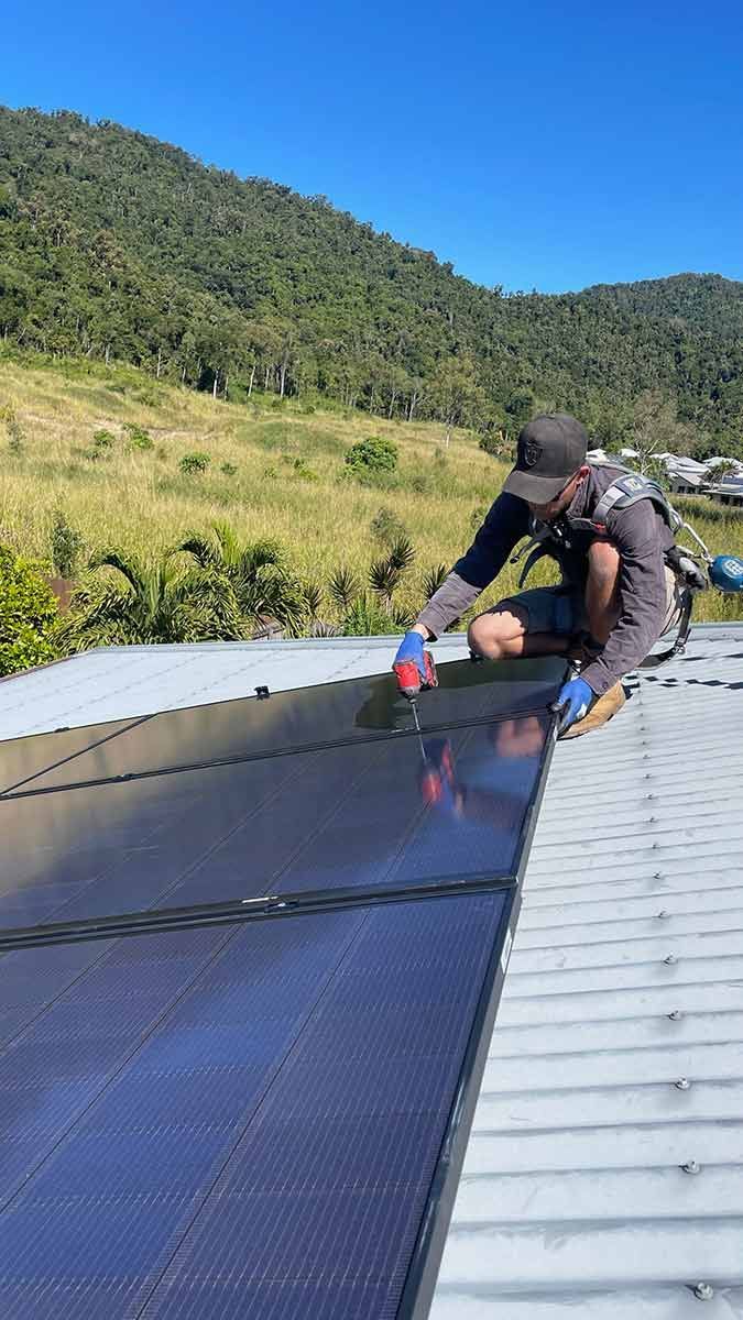 A Man Is Working On A Solar Panel On The Roof Of A Building — IPOWER Industries In Cannonvale, QLD