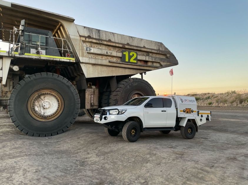 A White Truck Is Parked Next To A Large Dump Truck — IPOWER Industries In Bowen, QLD
