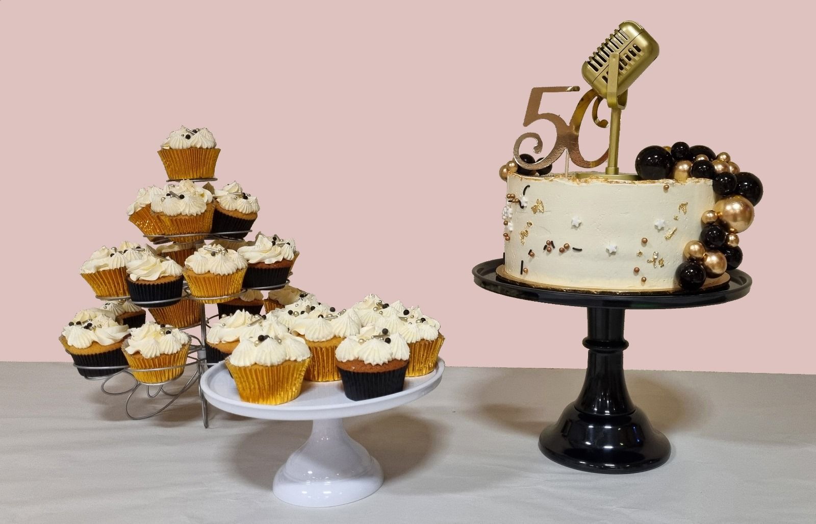 Een taart en cupcakes op een tafel met een roze achtergrond.