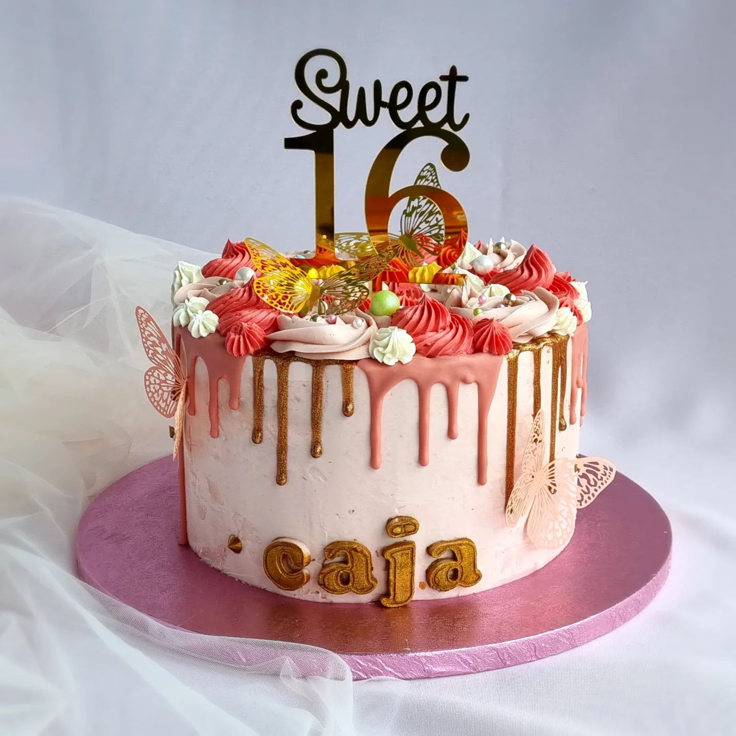 Een roze taart met een topper waarop staat sweet 16