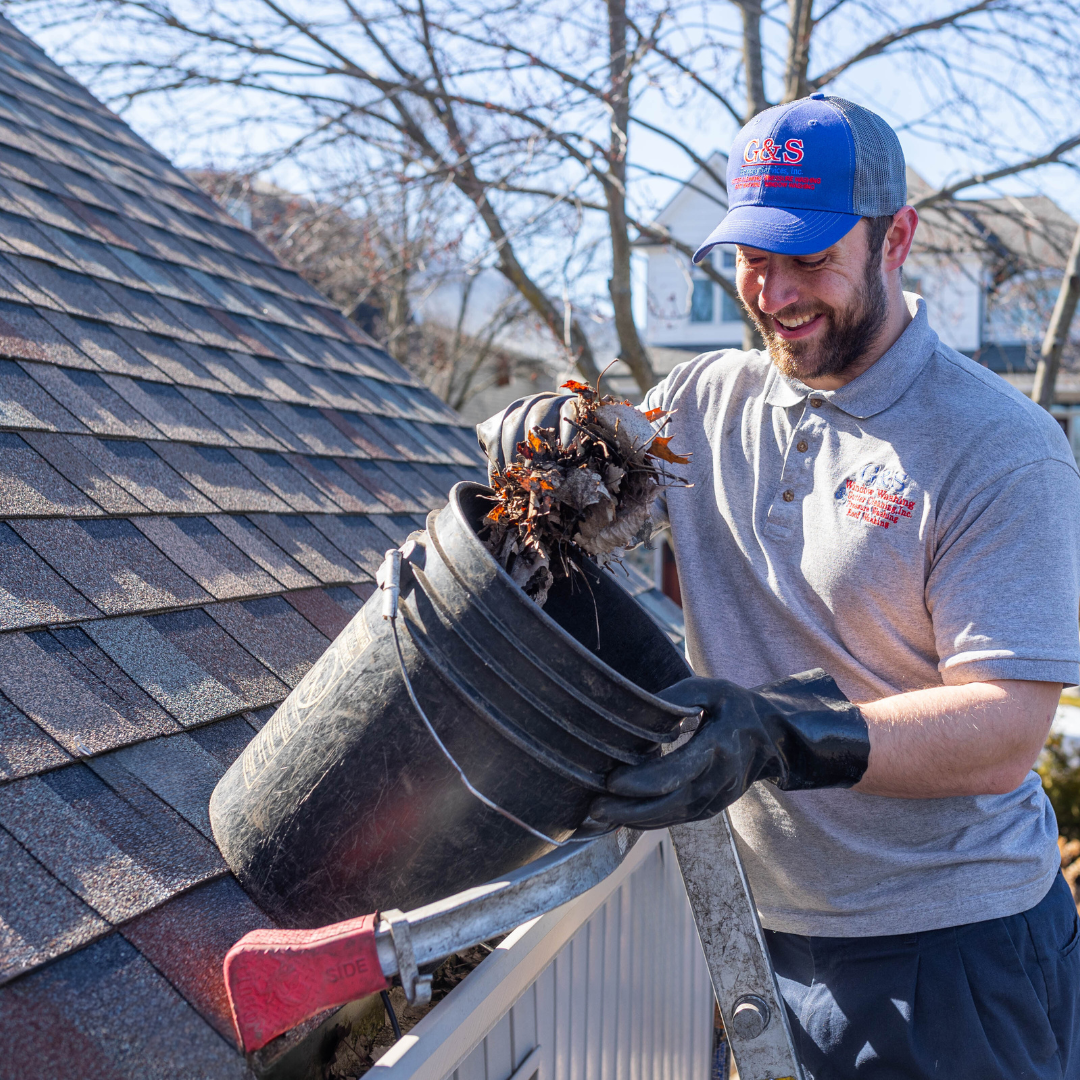 G&S employee removing leaves and debris from a residential gutter