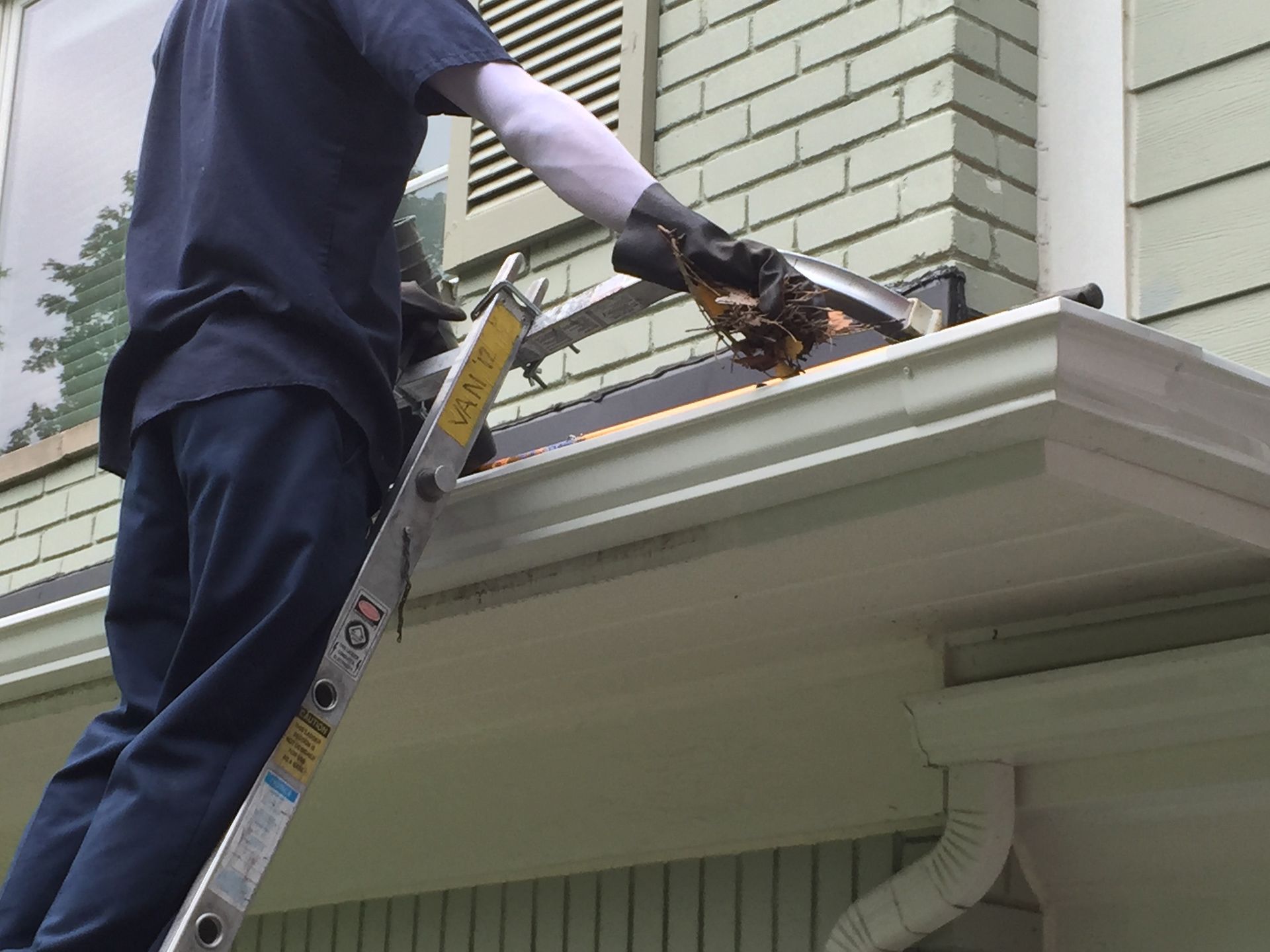 G&S employee removing debris from a gutter