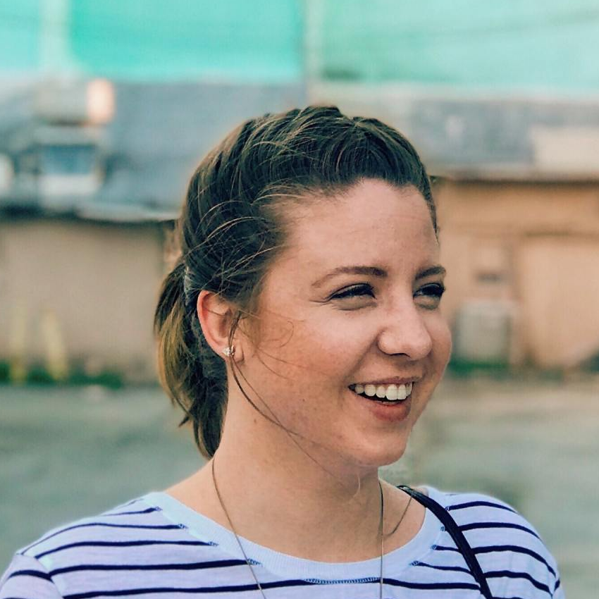 A woman in a striped shirt is smiling and looking to the side.