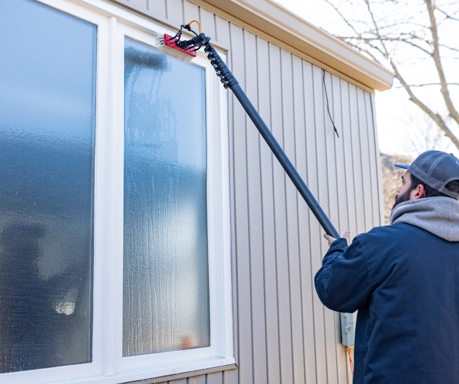 G&S employee cleaning a window with a squeegee