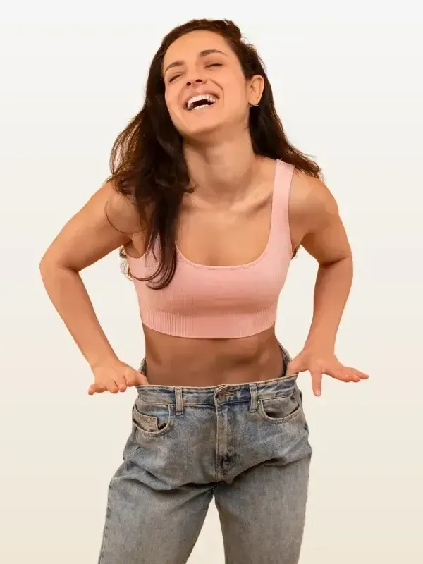 A woman in a pink crop top and jeans is laughing.