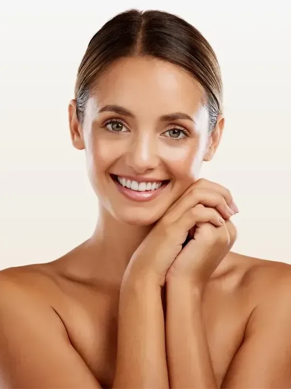 A woman is smiling with her hands on her face.