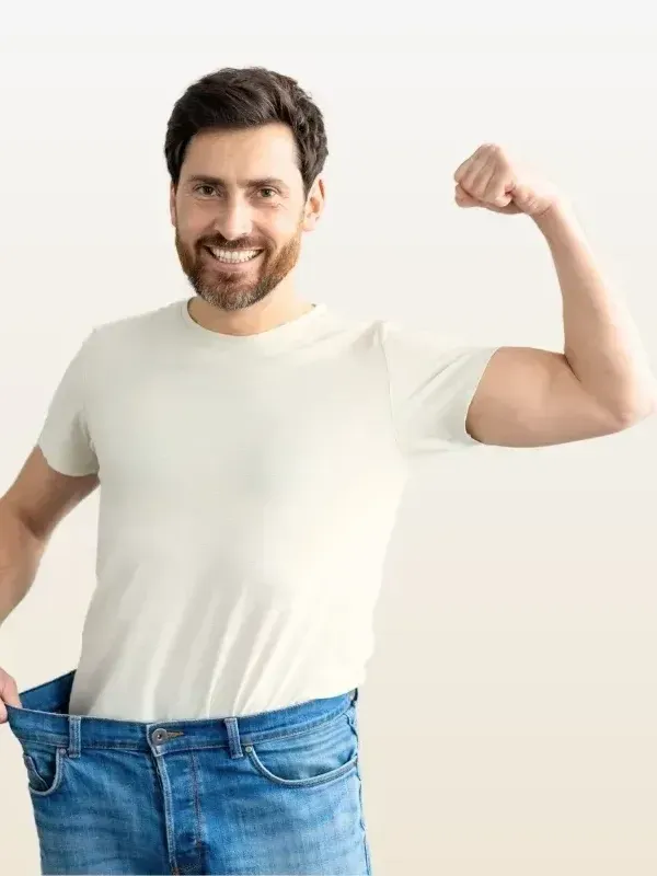 A man in a white t-shirt and blue jeans is flexing his muscles.