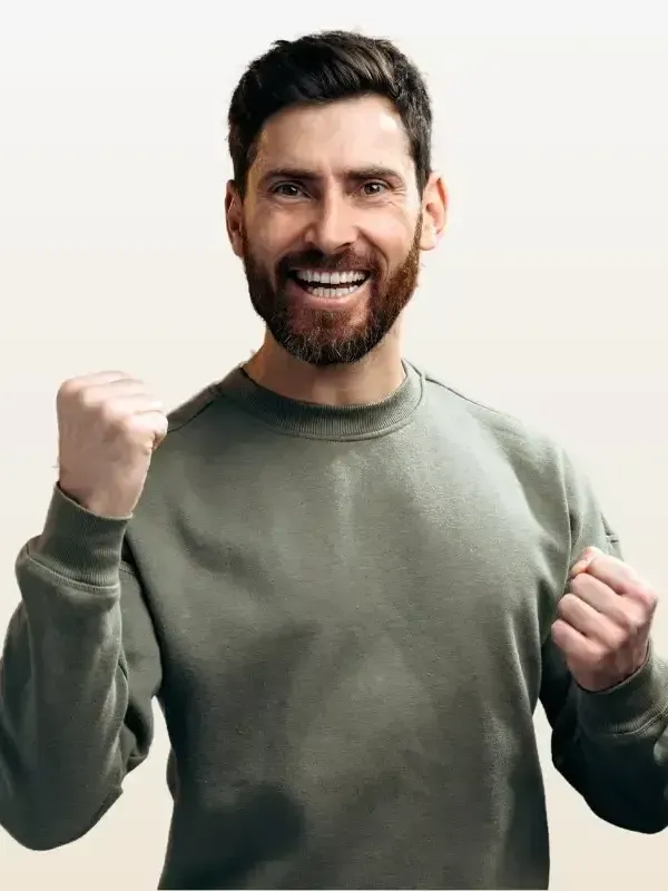 A man with a beard is smiling and holding his fist in the air.