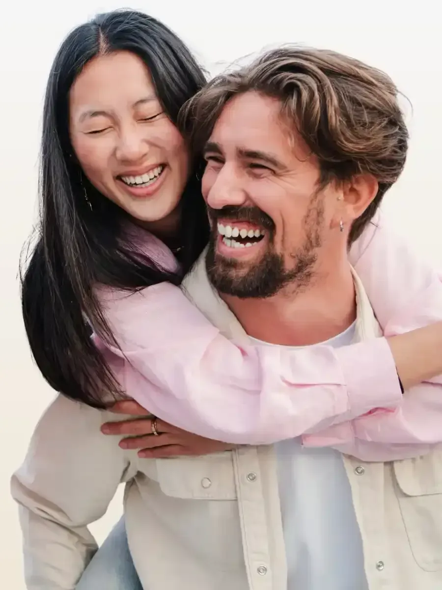 A man is carrying a woman on his back and they are smiling.