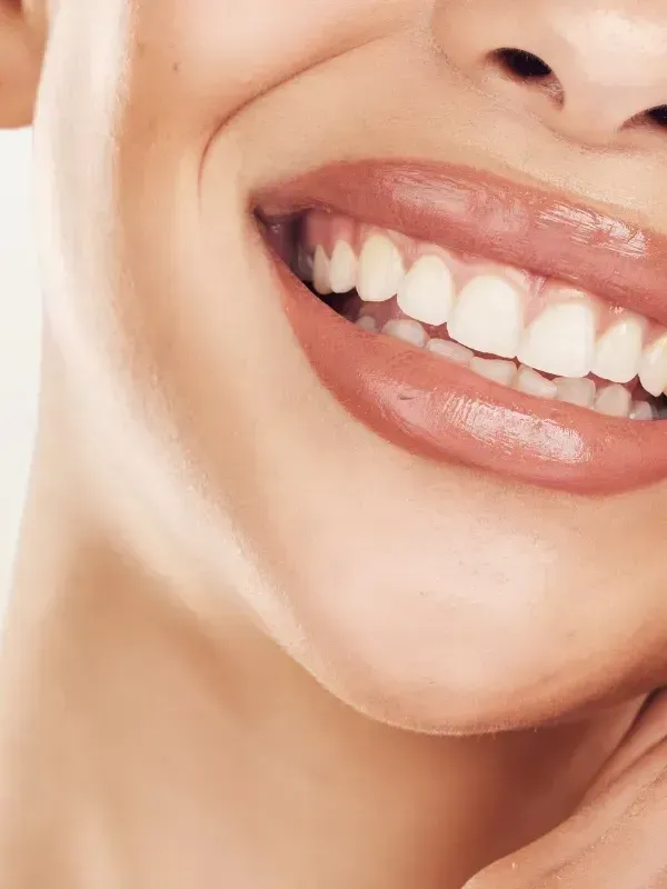 A close up of a woman 's smile with white teeth and pink lips.